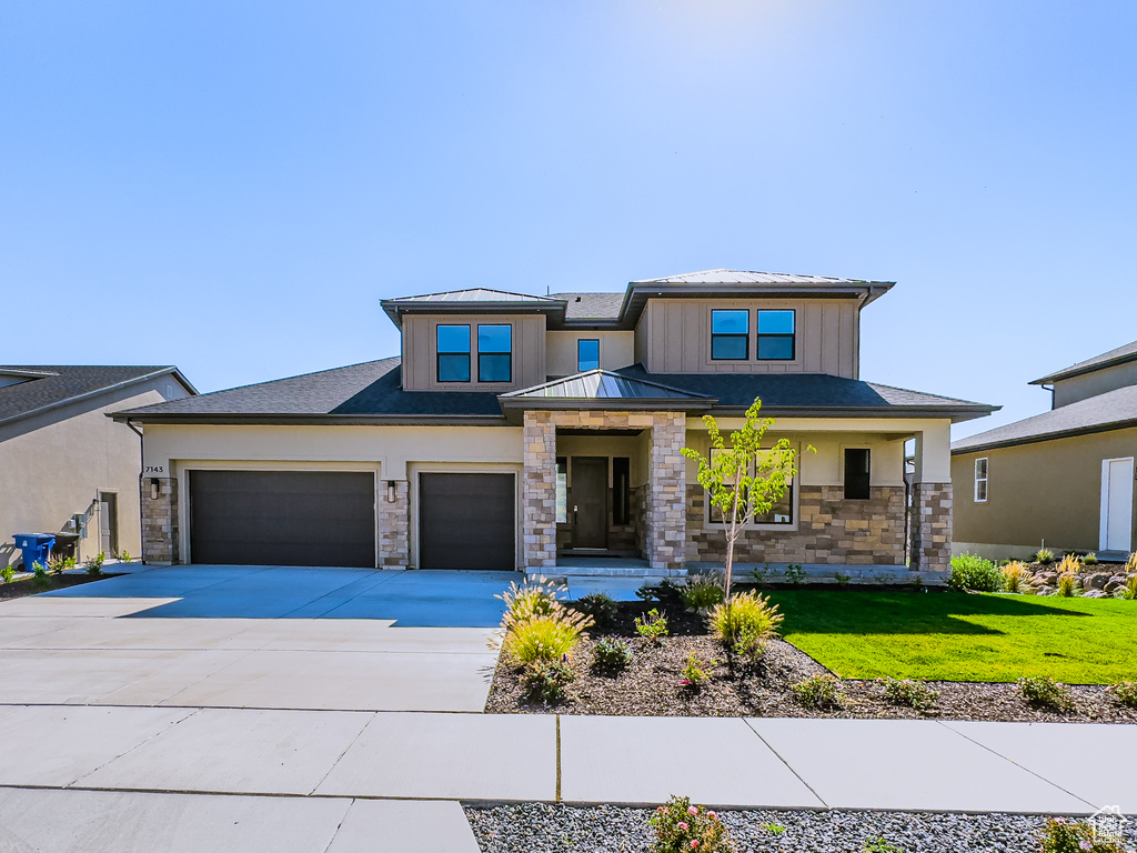 Prairie-style home featuring a front lawn, a porch, and a garage