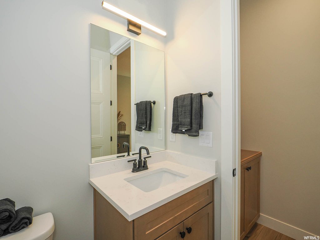 Bathroom with vanity, mirror, and hardwood flooring