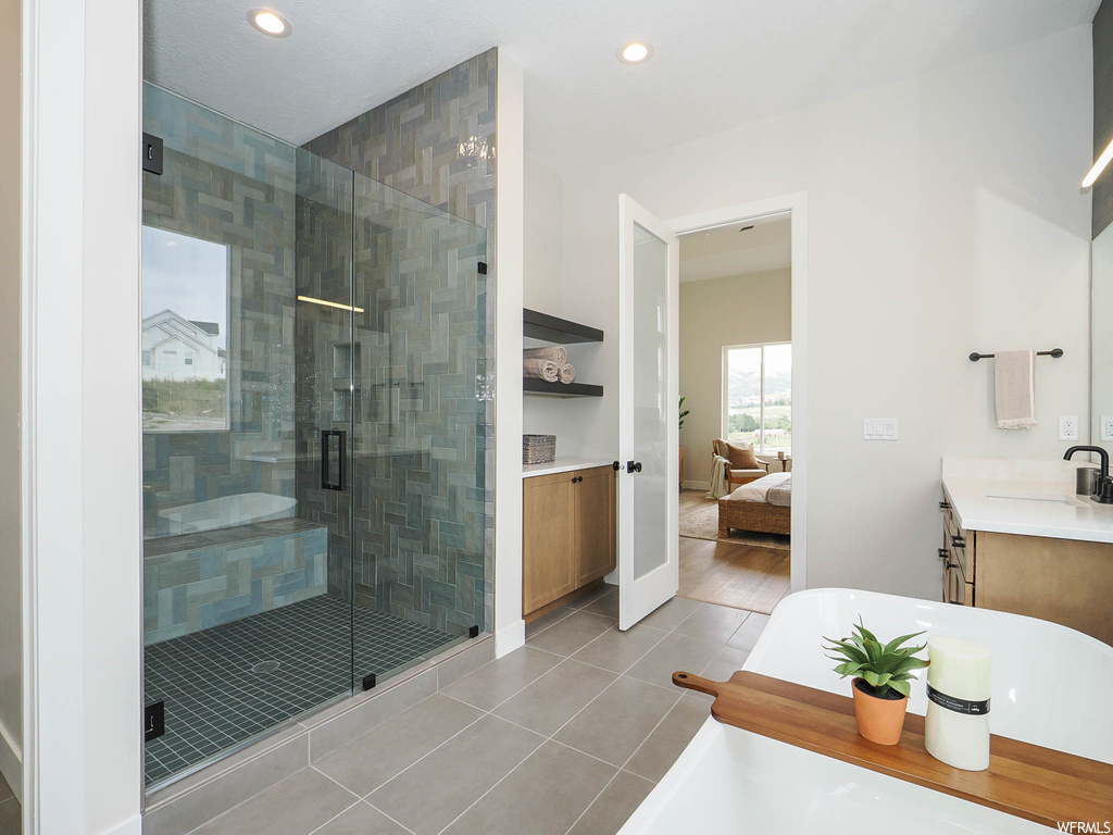 Bathroom featuring separate shower and tub, mirror, light tile floors, and vanity