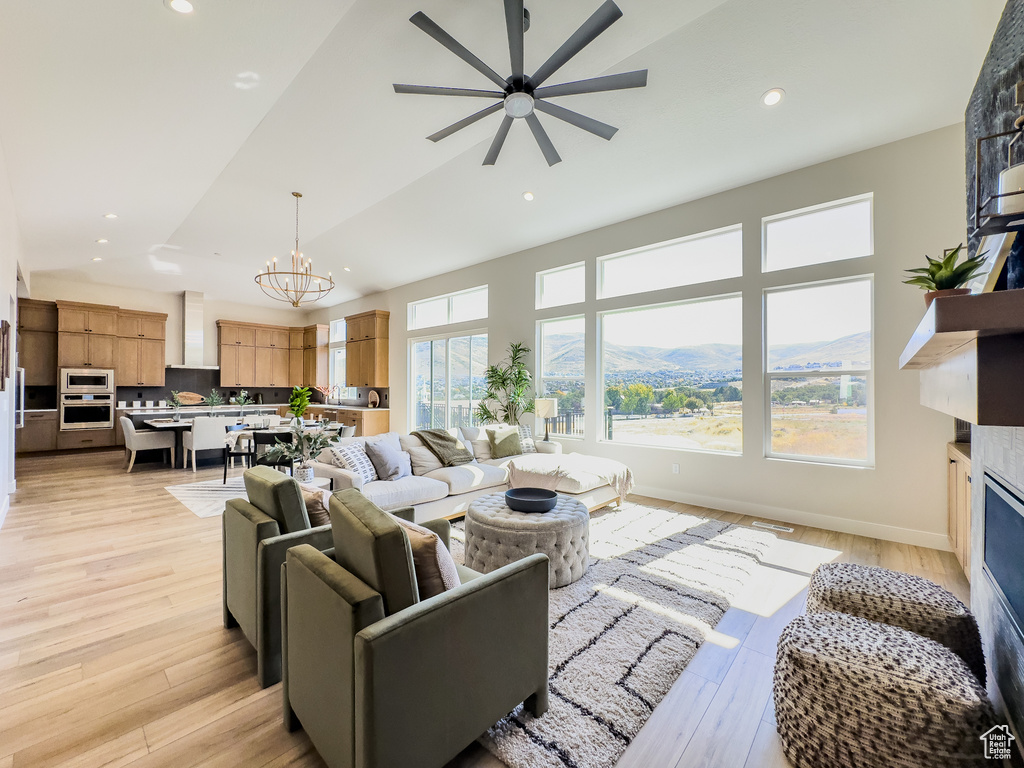 Living room with ceiling fan with notable chandelier, a mountain view, and light wood-type flooring