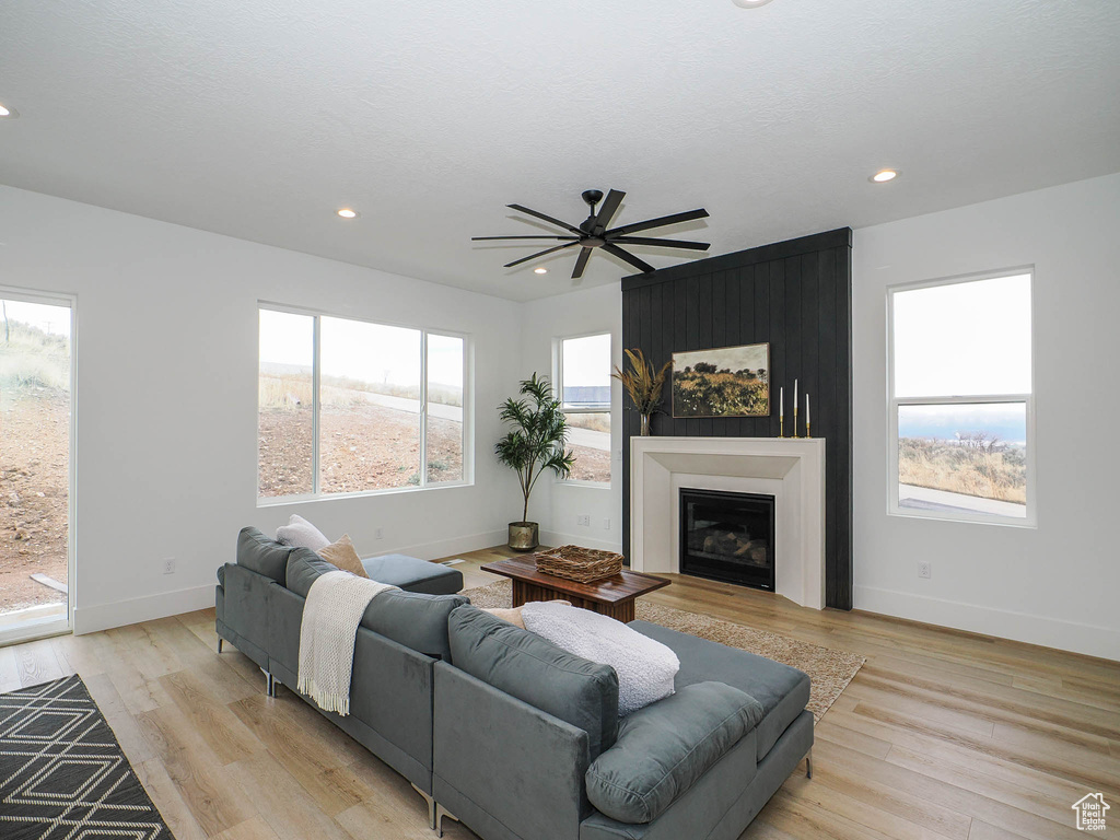 Living room with light hardwood / wood-style flooring, ceiling fan, and plenty of natural light