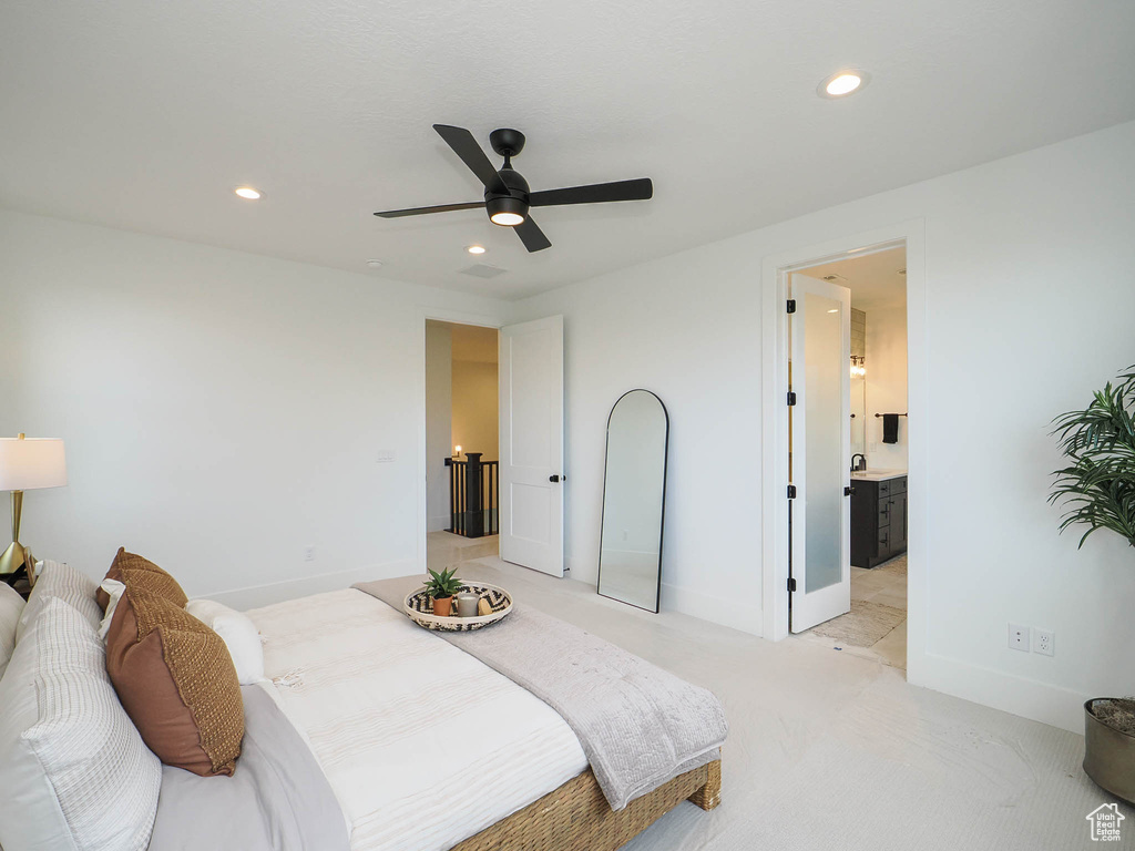 Bedroom with ensuite bathroom, light colored carpet, sink, and ceiling fan