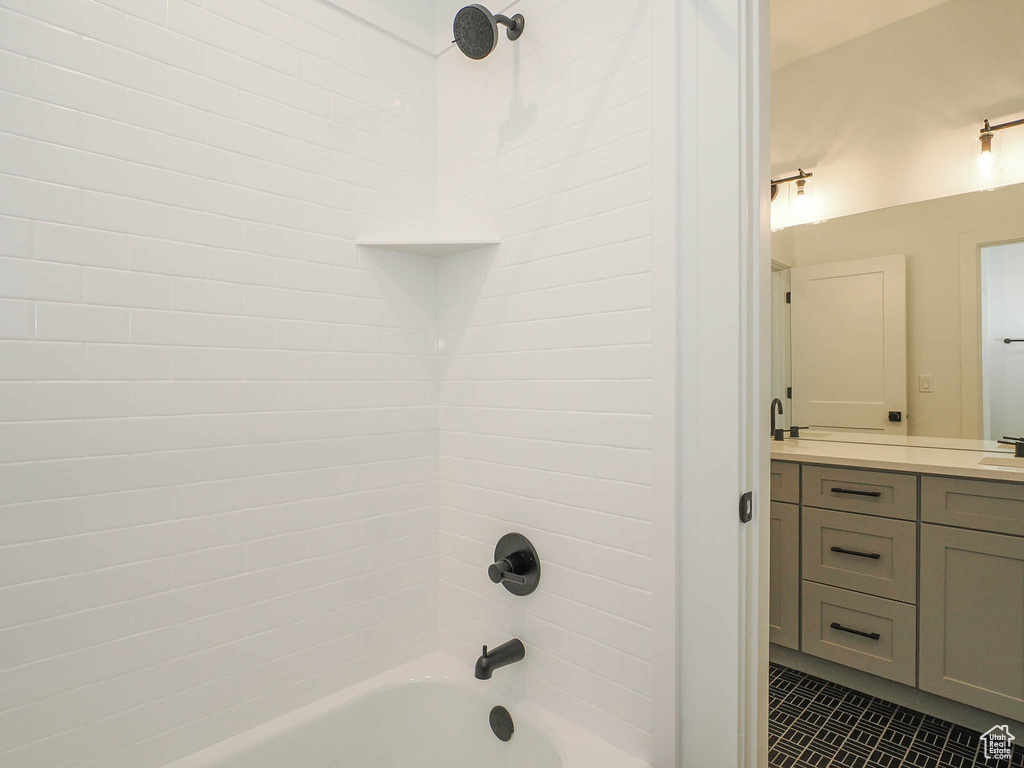 Bathroom featuring tiled shower / bath, vanity, and tile flooring