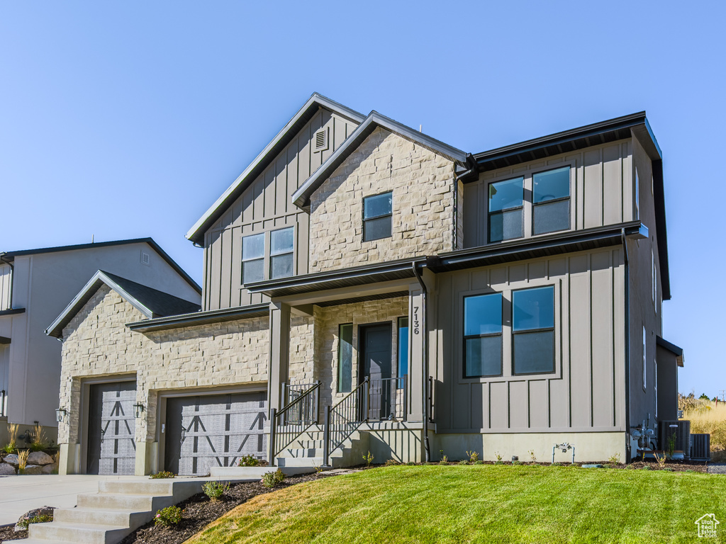 View of front of house with a front lawn, central air condition unit, and a garage