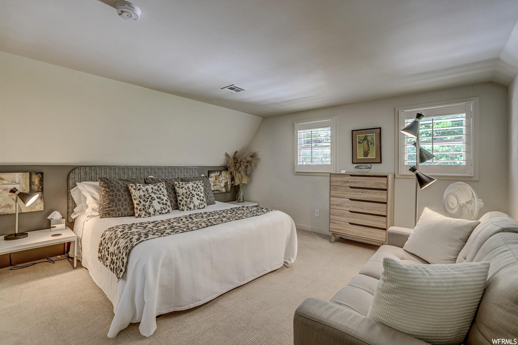 Bedroom featuring light carpet and vaulted ceiling