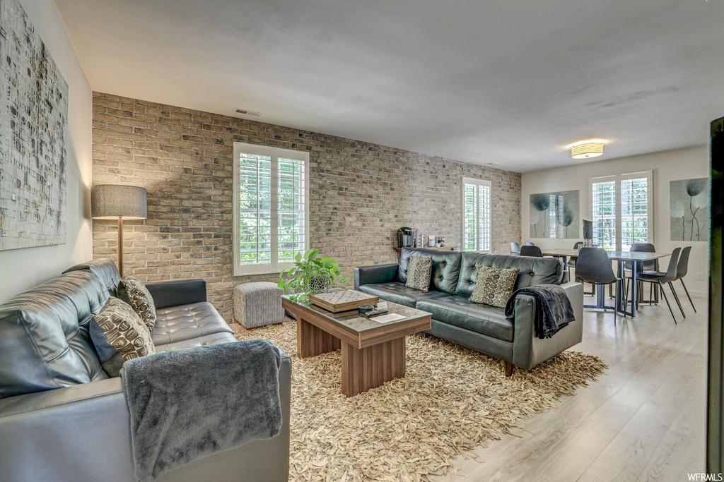Hardwood floored living room with brick wall