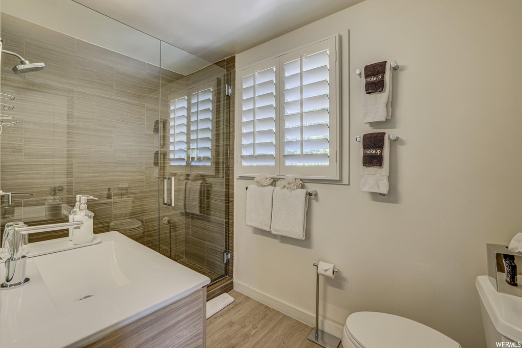 Bathroom featuring light hardwood floors, an enclosed shower, and vanity