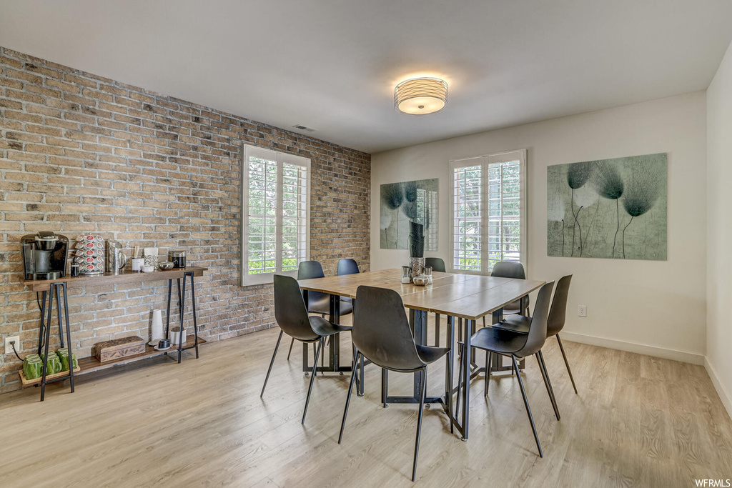 Dining room featuring brick wall and light hardwood flooring
