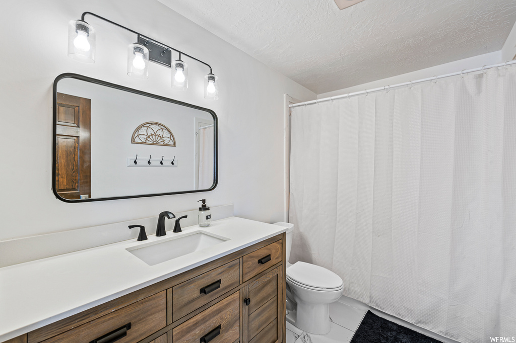 Bathroom featuring mirror, vanity, a textured ceiling, and light tile floors