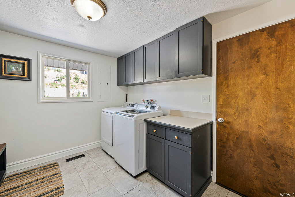 Laundry area with independent washer and dryer, a textured ceiling, and light tile floors