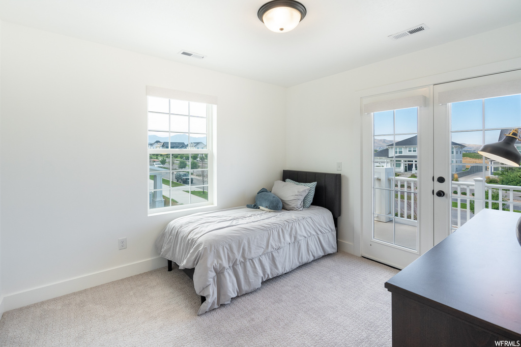 Bedroom featuring light carpet and multiple windows