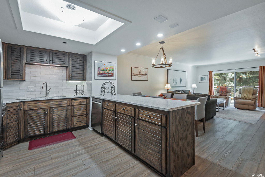 Kitchen featuring backsplash, dark brown cabinetry, and light hardwood floors