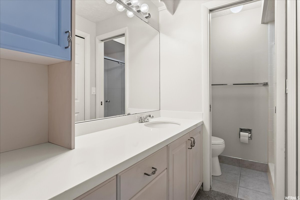 Bathroom with light tile flooring, vanity with extensive cabinet space, and mirror
