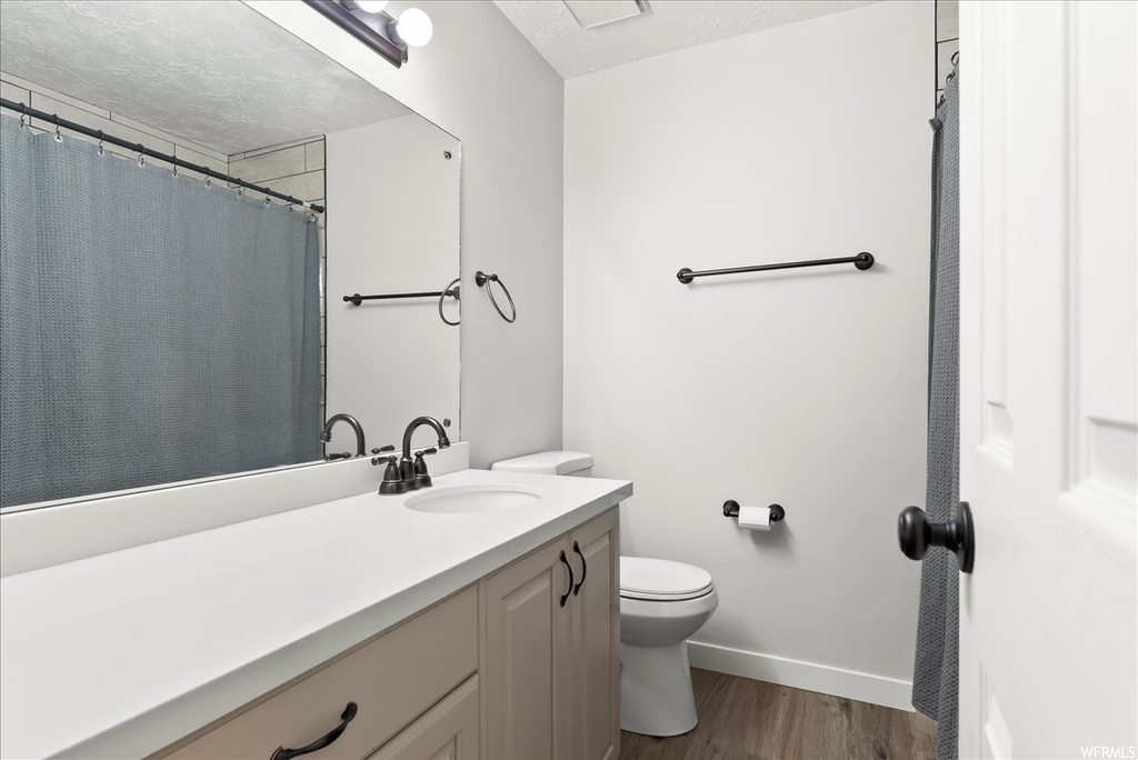Bathroom with mirror, vanity, and hardwood flooring