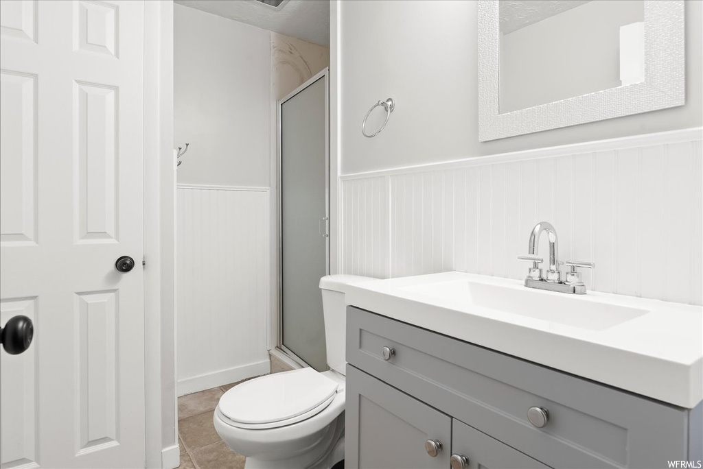 Bathroom featuring light tile floors, vanity, mirror, and a shower with shower door