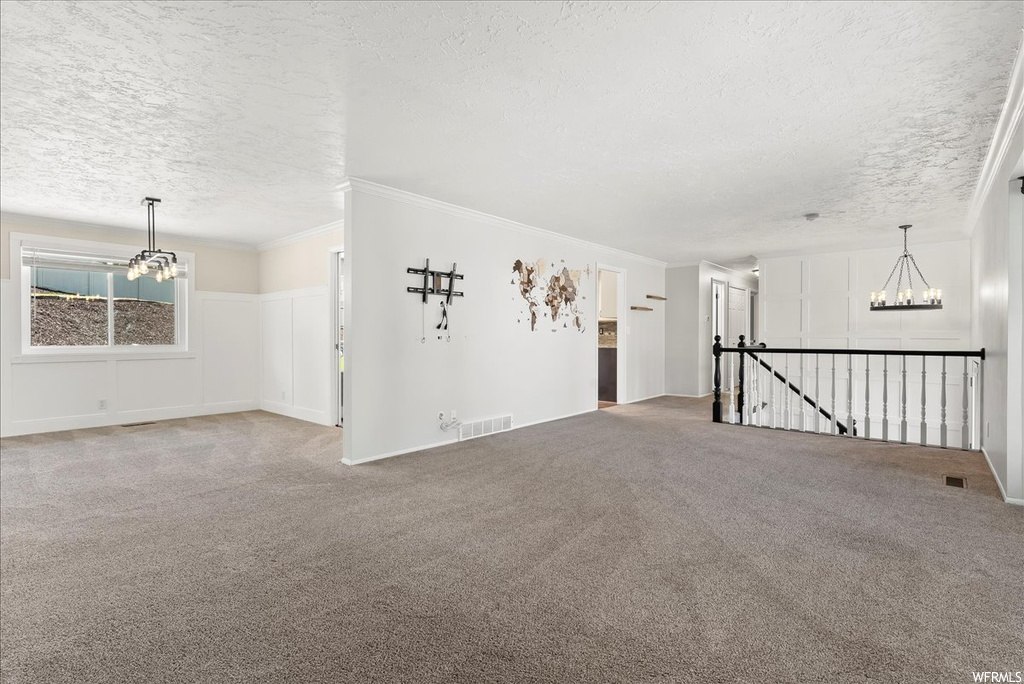 Unfurnished room featuring crown molding, a textured ceiling, and light carpet