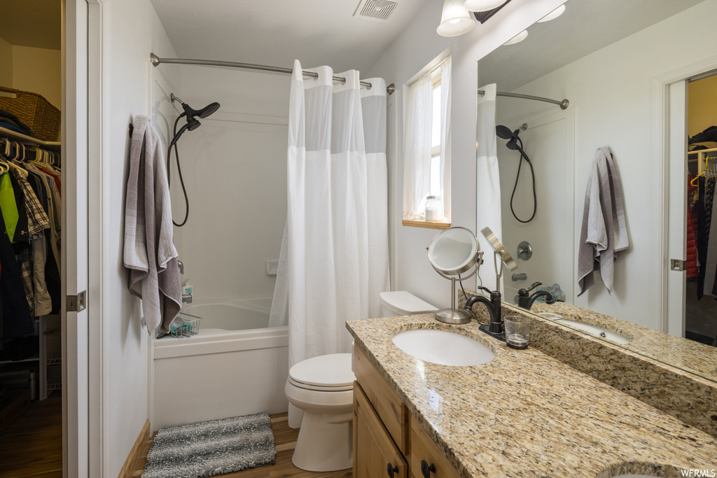 Full bathroom with hardwood floors, shower / bath combo, vanity, and mirror