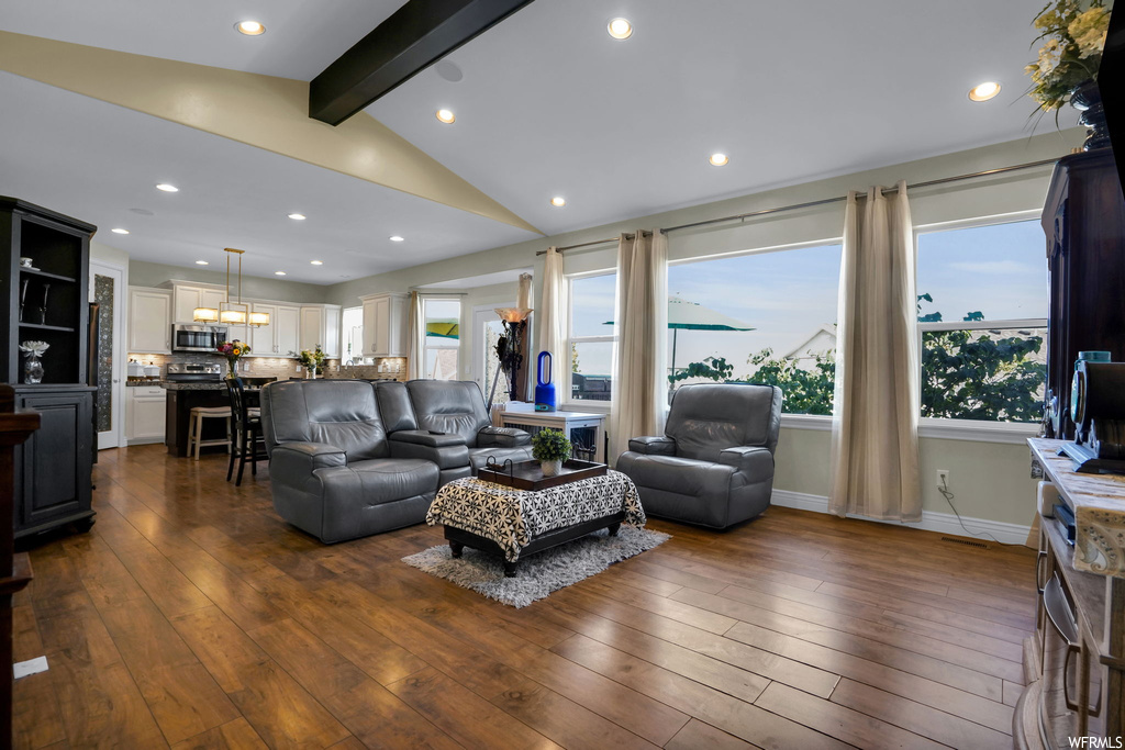 Hardwood floored living room featuring vaulted ceiling with beams