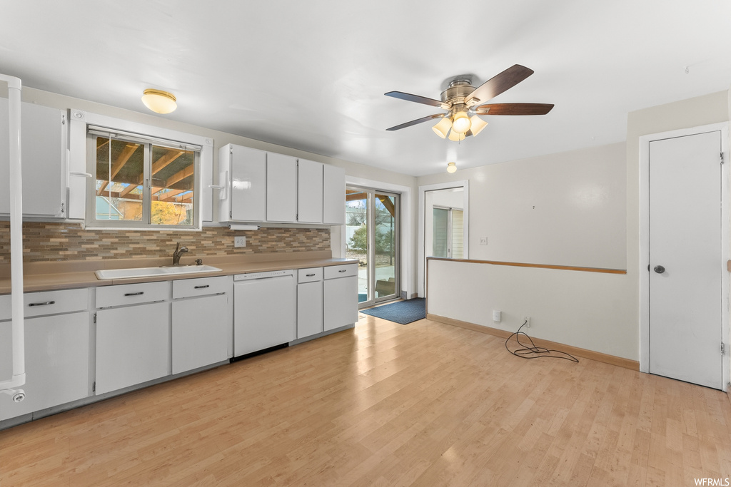 Kitchen with sink, light wood-type flooring, ceiling fan, white dishwasher, and white cabinetry