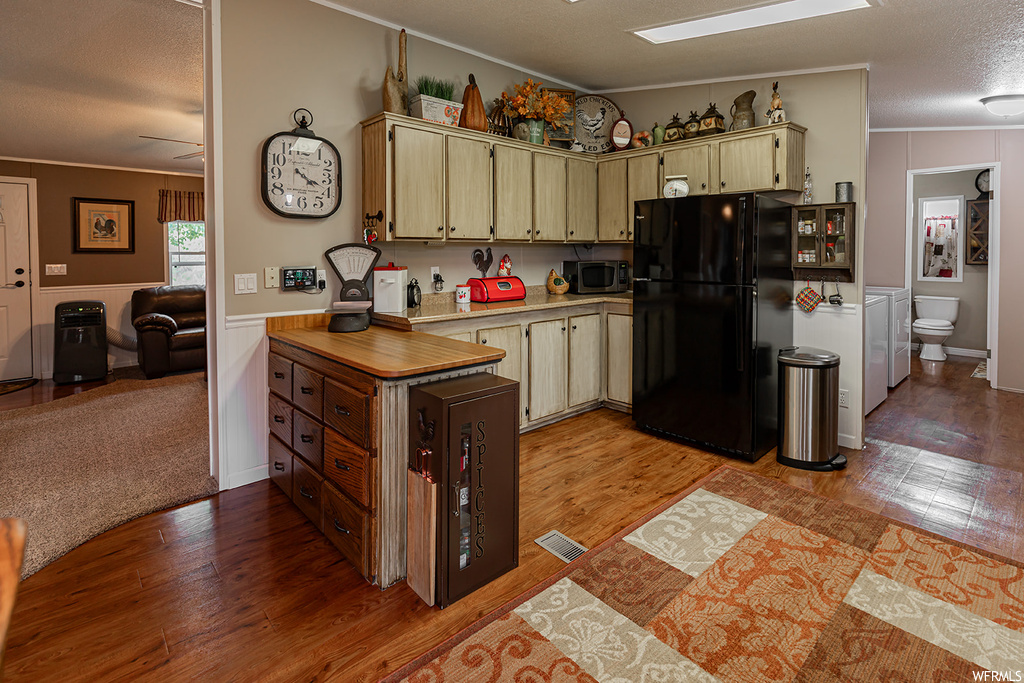 Kitchen featuring light countertops, light carpet, ceiling fan, black fridge, and a textured ceiling