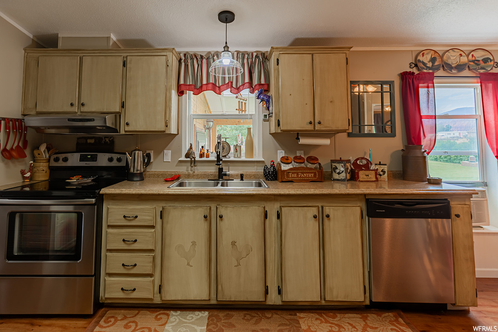 Kitchen with ornamental molding, appliances with stainless steel finishes, and wood-type flooring