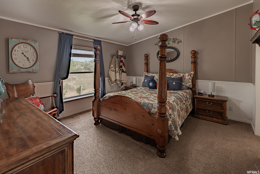 Carpeted bedroom featuring ceiling fan, a textured ceiling, and ornamental molding