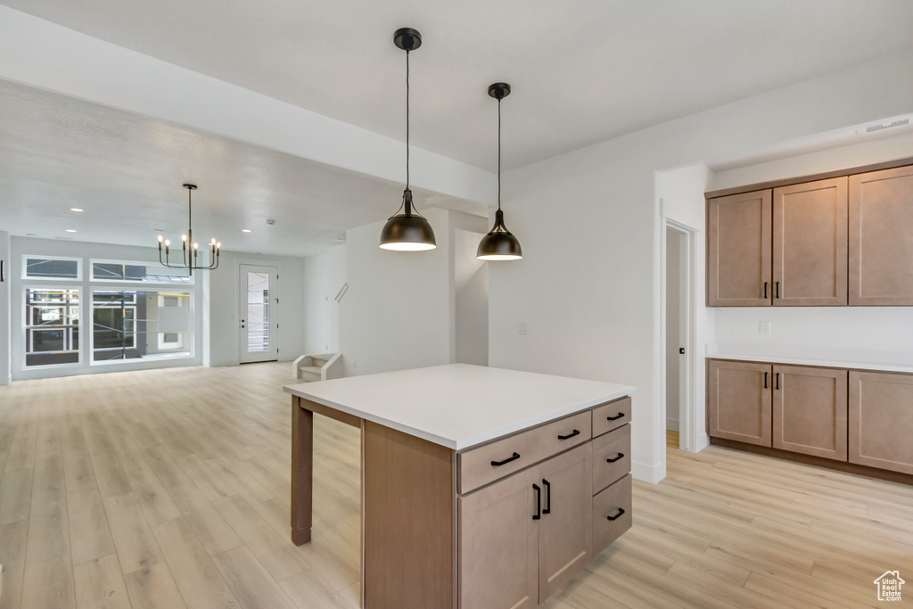 Kitchen with a center island, pendant lighting, light hardwood / wood-style flooring, and a notable chandelier