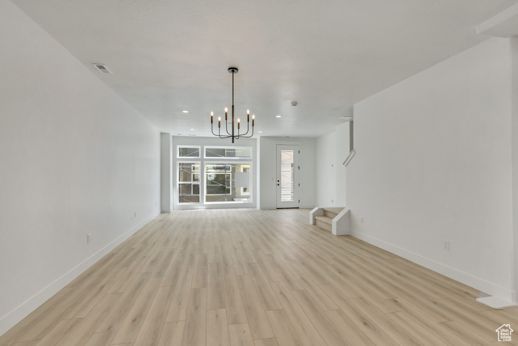 Unfurnished living room with light hardwood / wood-style flooring and an inviting chandelier