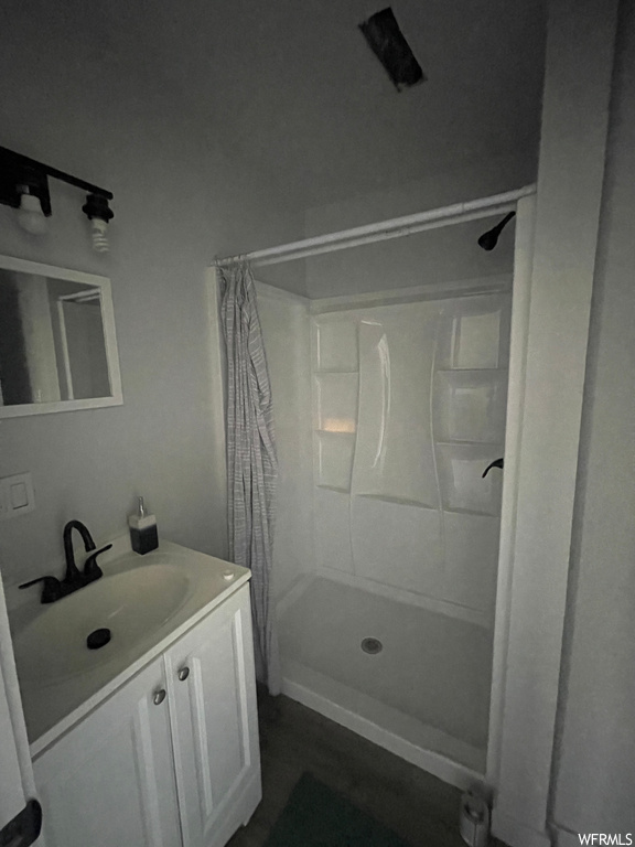 Bathroom featuring mirror, a shower with shower curtain, and vanity with extensive cabinet space