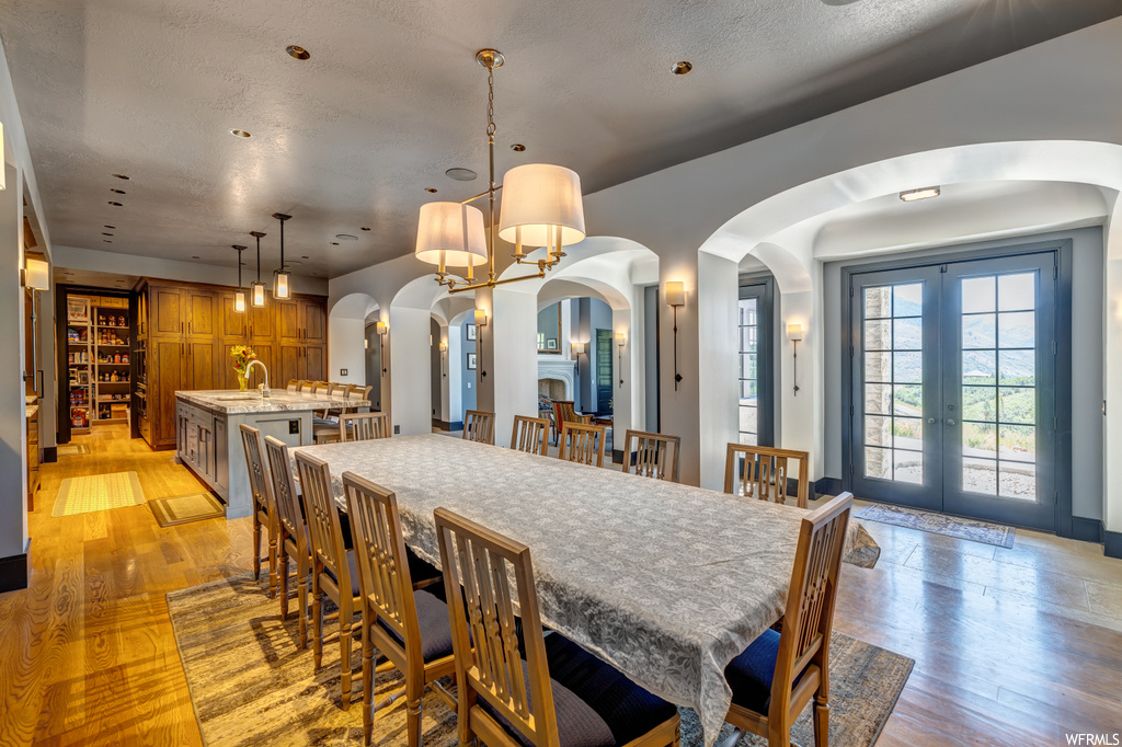 Hardwood floored dining space with french doors and a chandelier