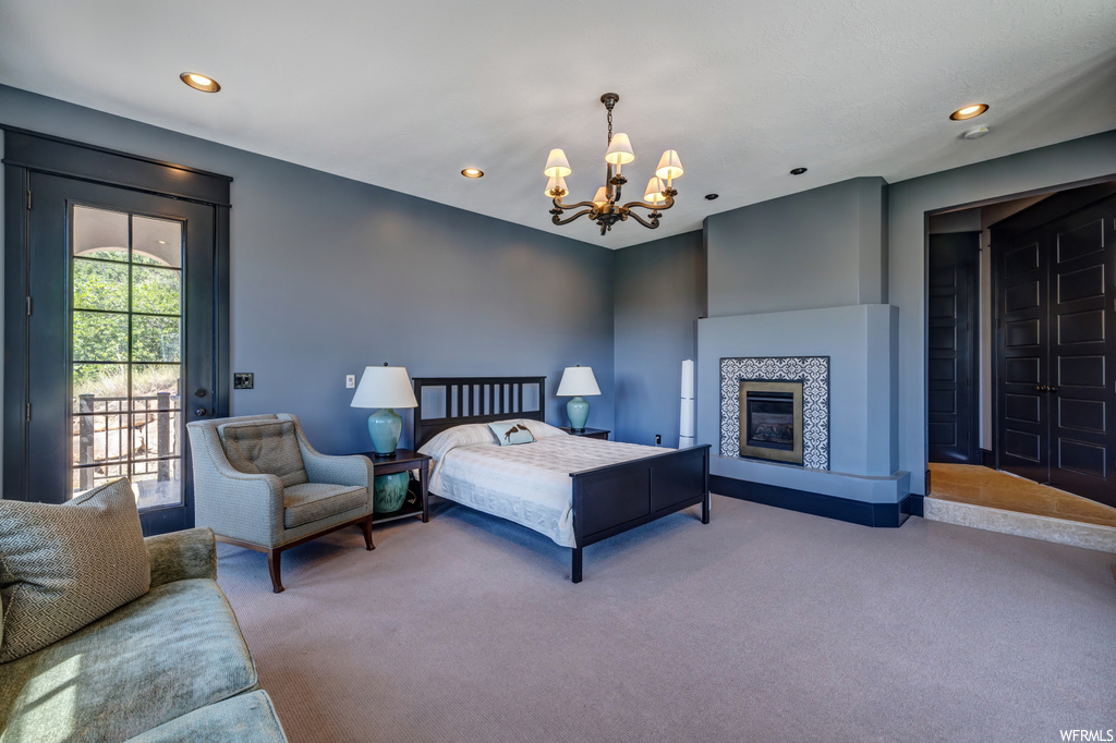 Bedroom featuring a fireplace, a chandelier, and light carpet