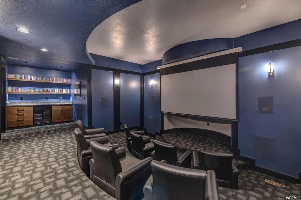 Home theater room with dark carpet and a textured ceiling