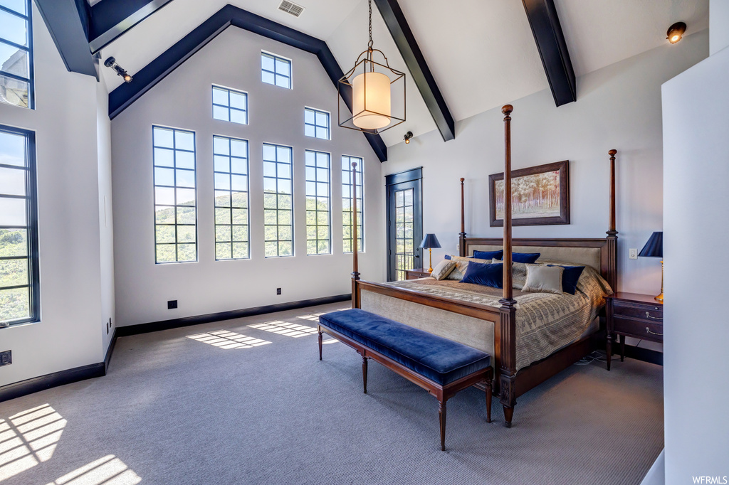Carpeted bedroom featuring a high ceiling and lofted ceiling with beams