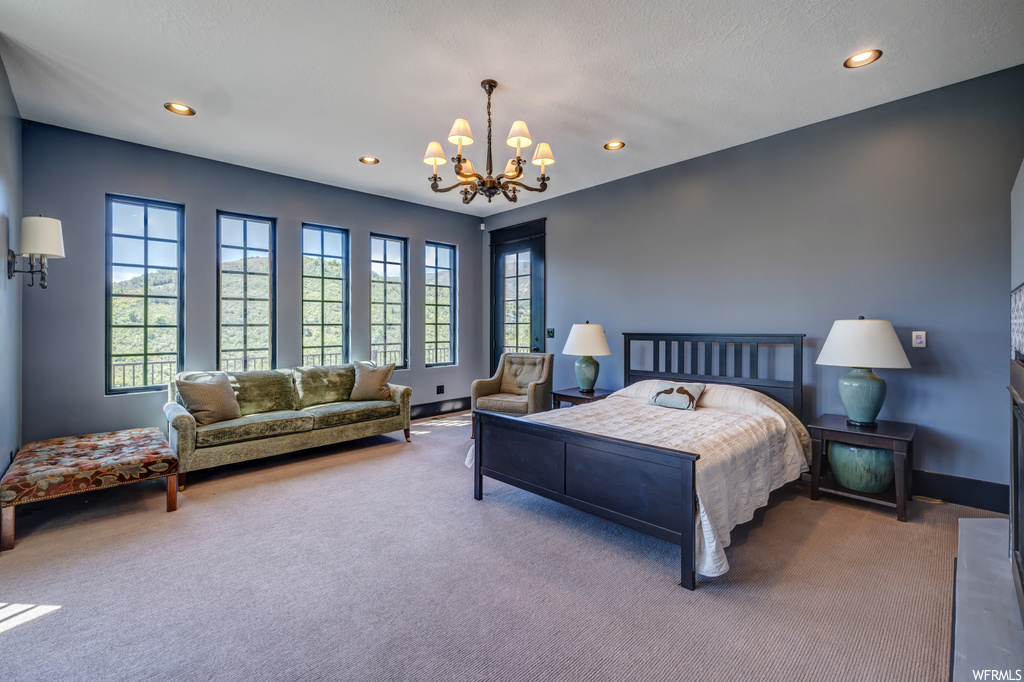 Bedroom featuring light carpet, multiple windows, and a notable chandelier