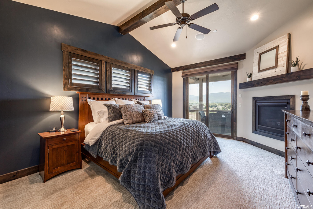 Carpeted bedroom with ceiling fan, a fireplace, and vaulted ceiling with beams