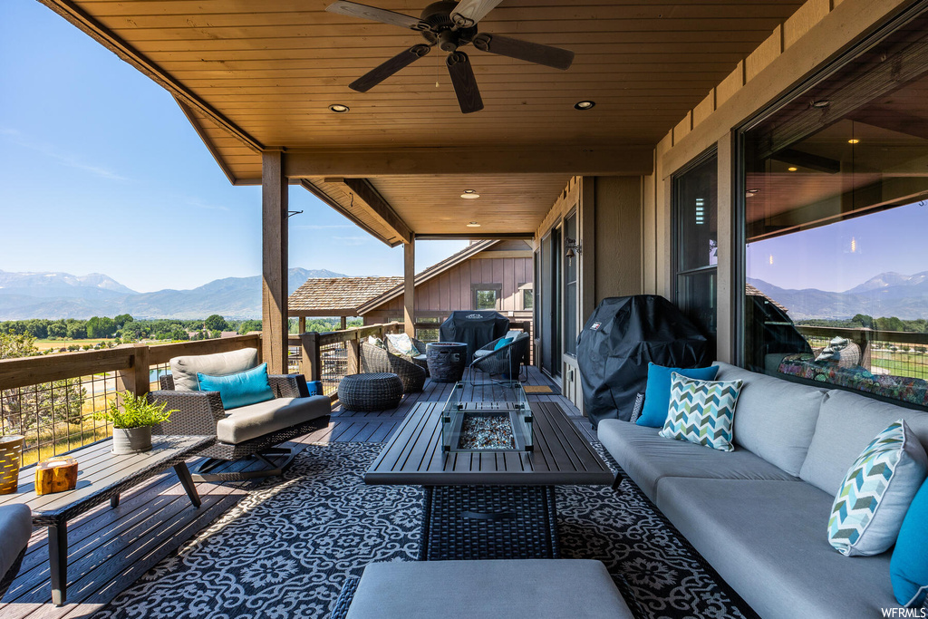 View of patio with ceiling fan, an outdoor living space, and a deck with mountain view