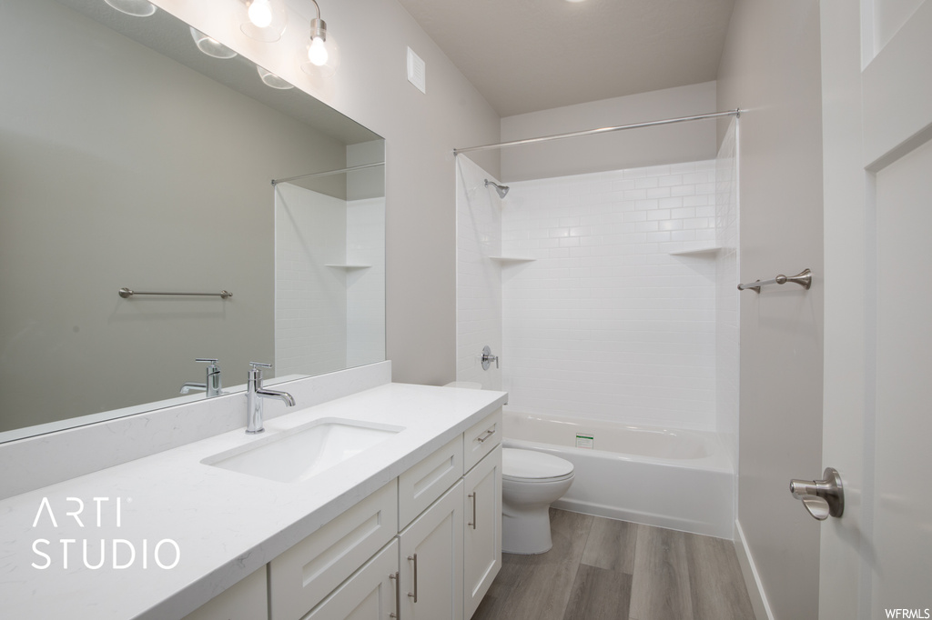 Full bathroom featuring hardwood flooring, mirror, large vanity, and tub / shower combination