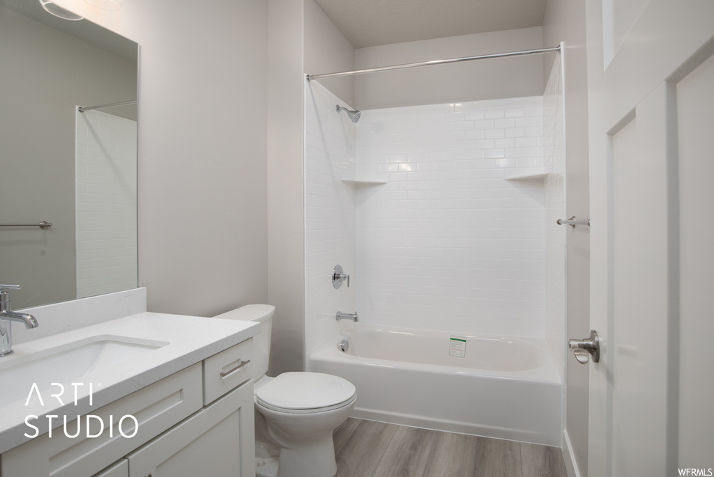 Full bathroom with shower / washtub combination, wood-type flooring, vanity with extensive cabinet space, and mirror