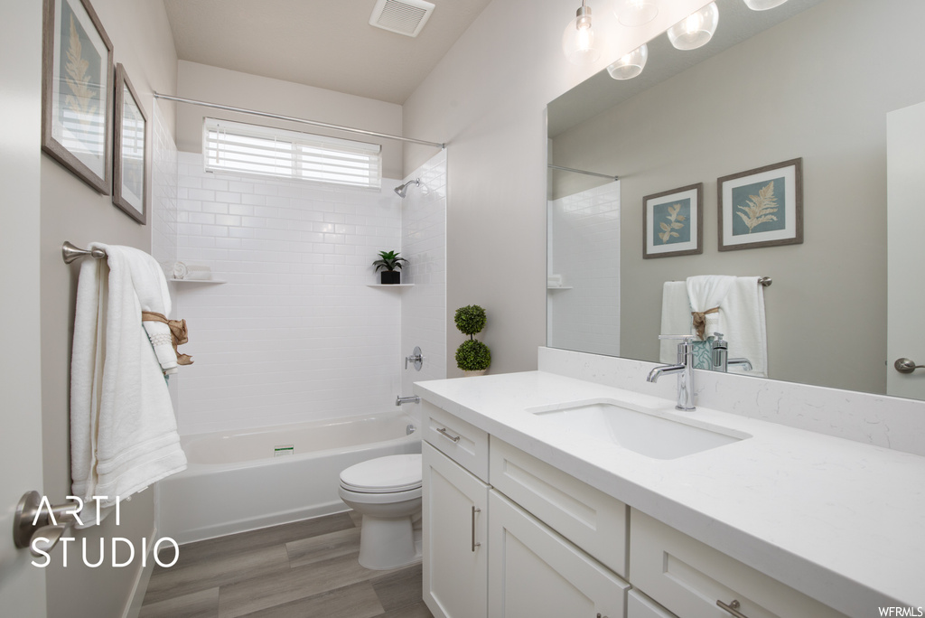 Full bathroom featuring tiled shower / bath combo, hardwood flooring, mirror, and oversized vanity