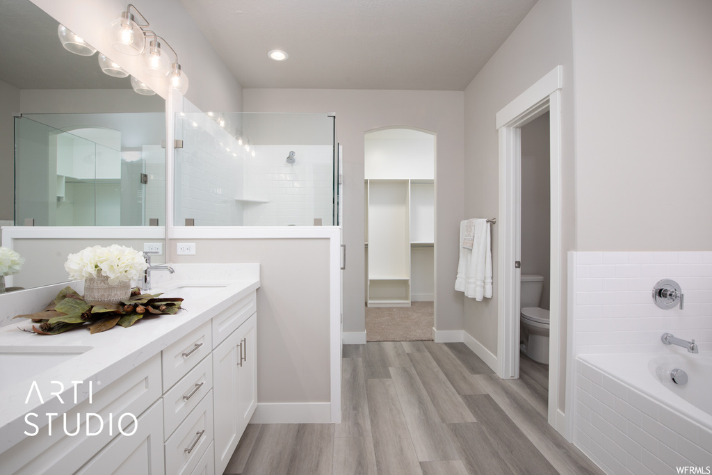 Full bathroom with mirror, separate shower and tub, dual large bowl vanity, and hardwood floors