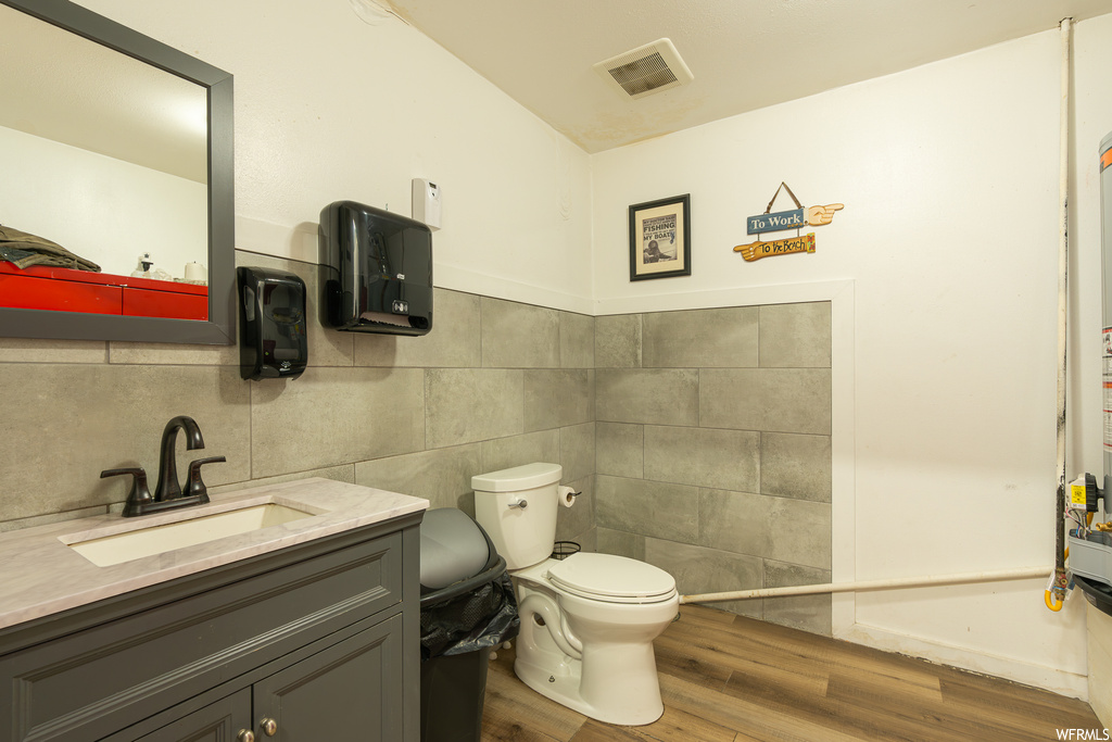 Bathroom featuring light hardwood floors, tile walls, mirror, and oversized vanity