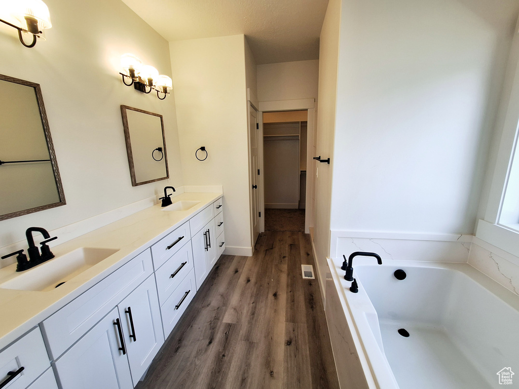 Bathroom featuring oversized vanity, dual sinks, hardwood / wood-style flooring, and tiled bath