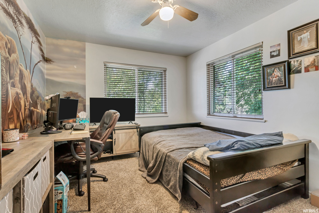 Bedroom with light carpet, ceiling fan, and a textured ceiling