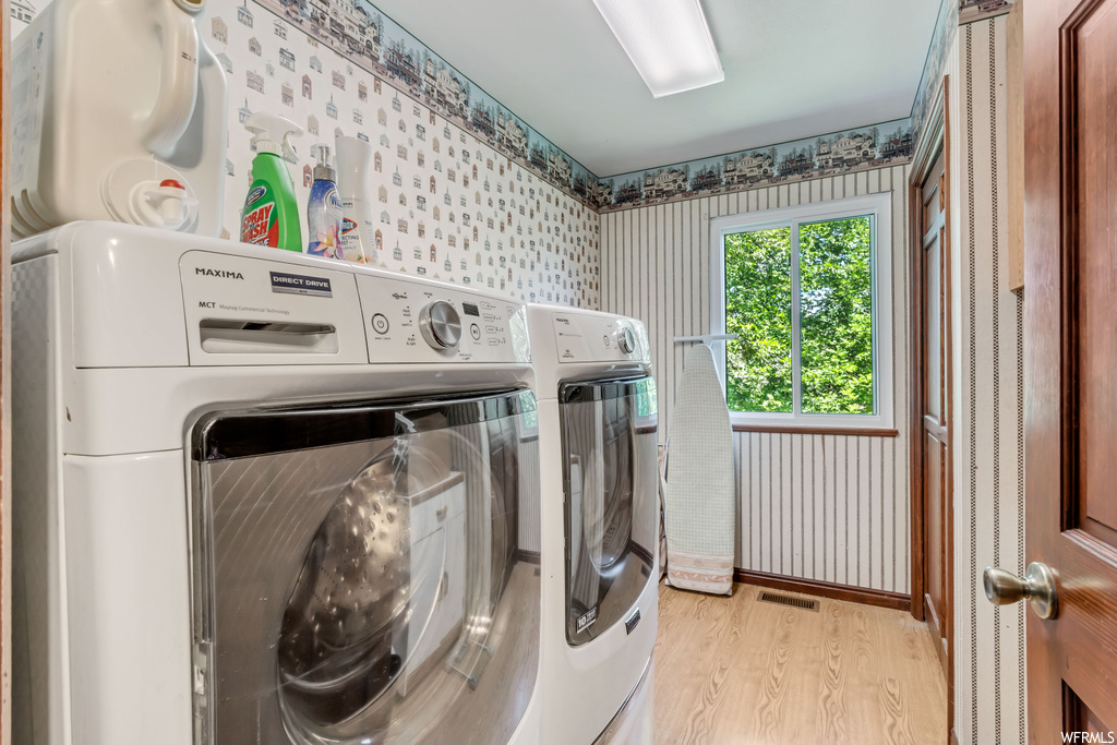 Clothes washing area with light parquet floors and washing machine and clothes dryer