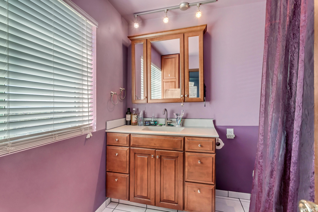 Bathroom featuring mirror, vanity, tile flooring, and rail lighting
