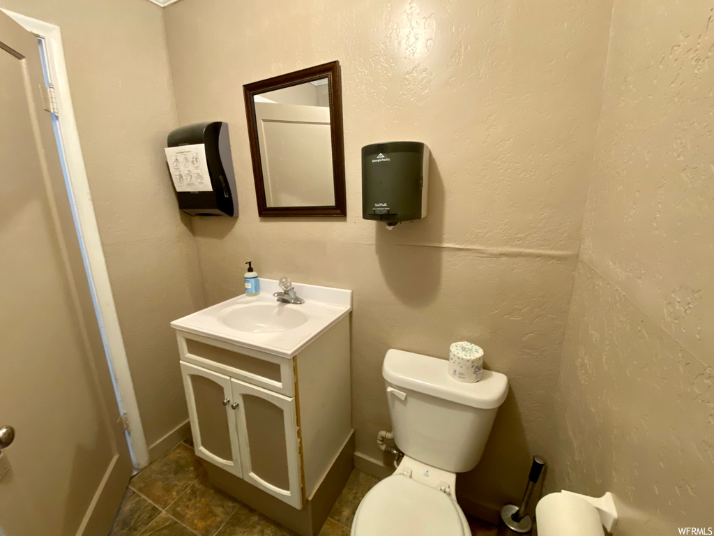 Bathroom with mirror, dark tile floors, and vanity