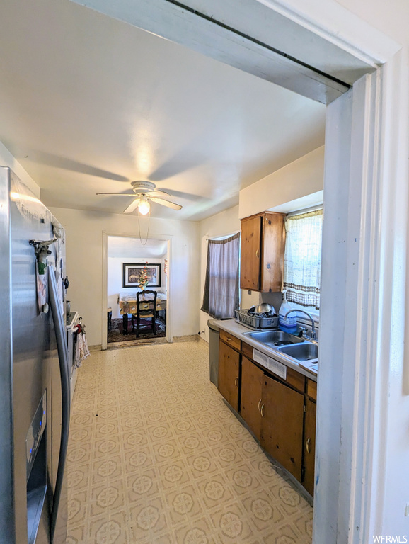 Kitchen featuring brown cabinets, light tile floors, and ceiling fan