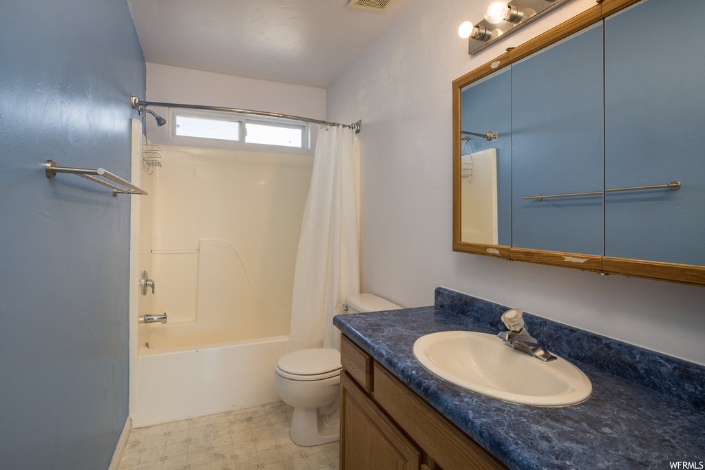 Full bathroom featuring vanity, shower / bath combo with shower curtain, toilet, and tile floors
