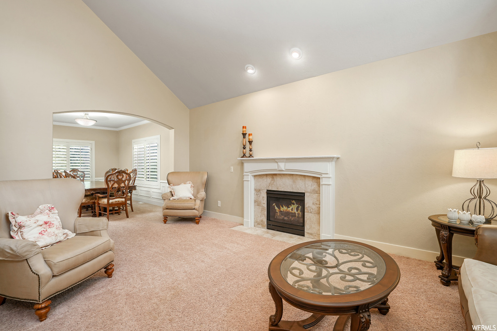 Living room with light carpet, vaulted ceiling, a high ceiling, and a fireplace