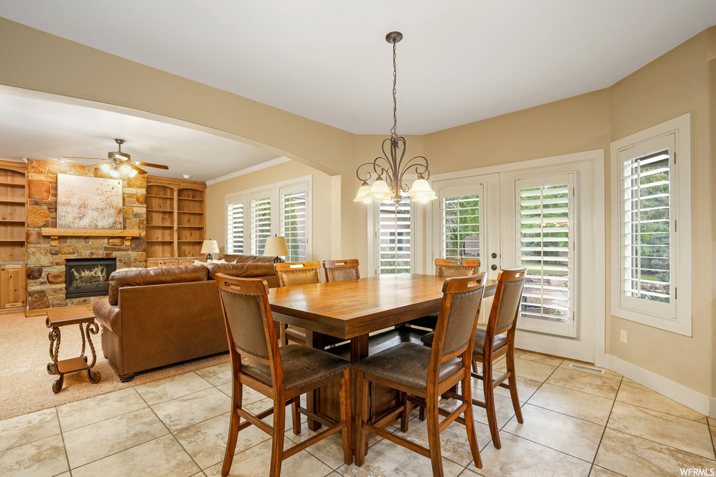 Dining room featuring a wealth of natural light, built in features, ceiling fan, a fireplace, and light tile flooring